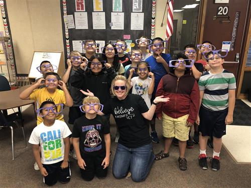 Photo of Newell students with their teacher in a classroom wearing large sunglasses